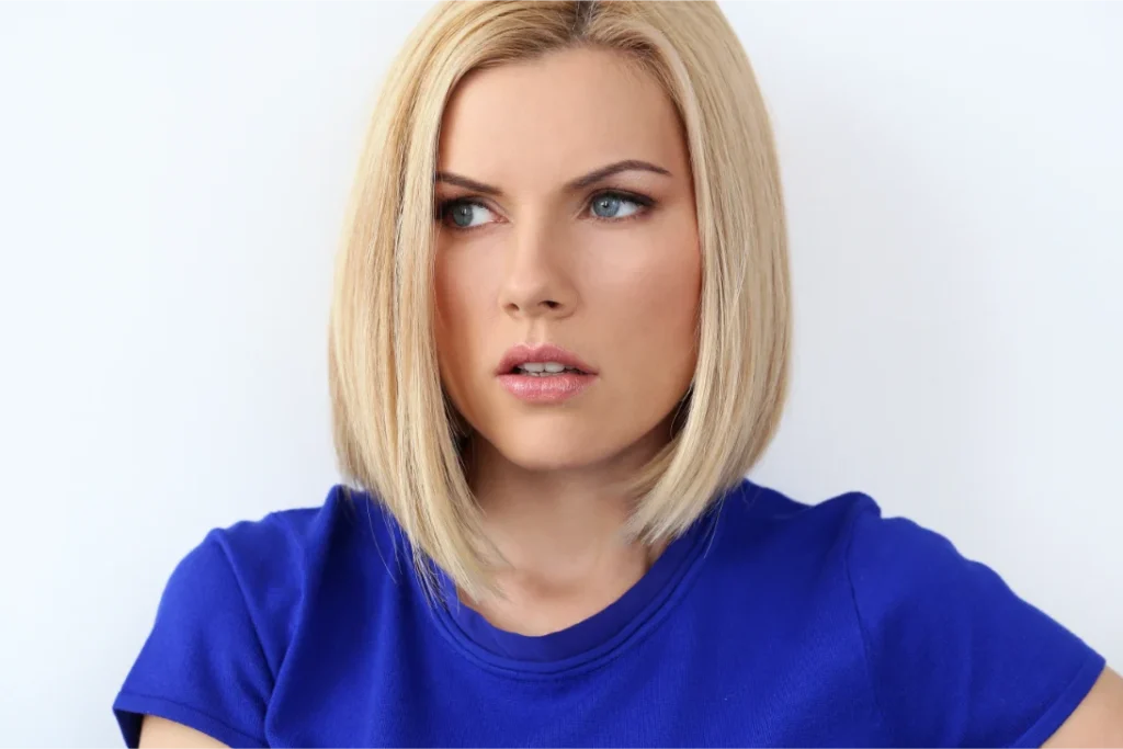 A woman in a blue shirt with a blonde classic blunt bob hairstyle.